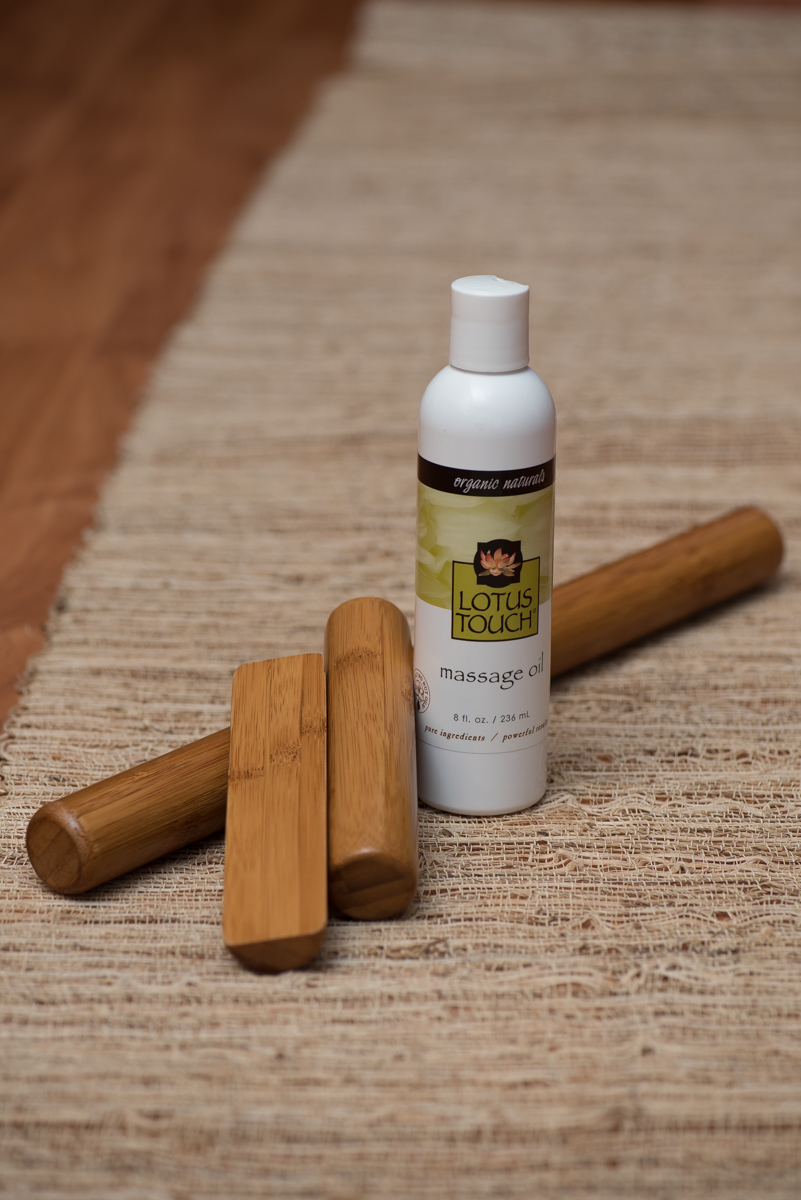 Bamboo massage sticks beside a bottle of massage oil